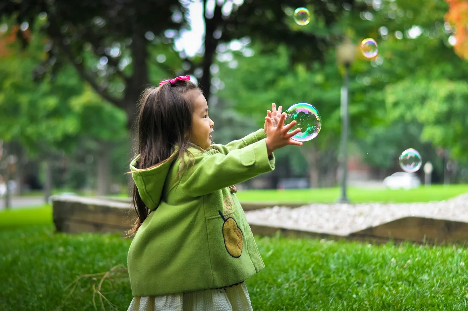 A toddler chasing bubbles on the grass