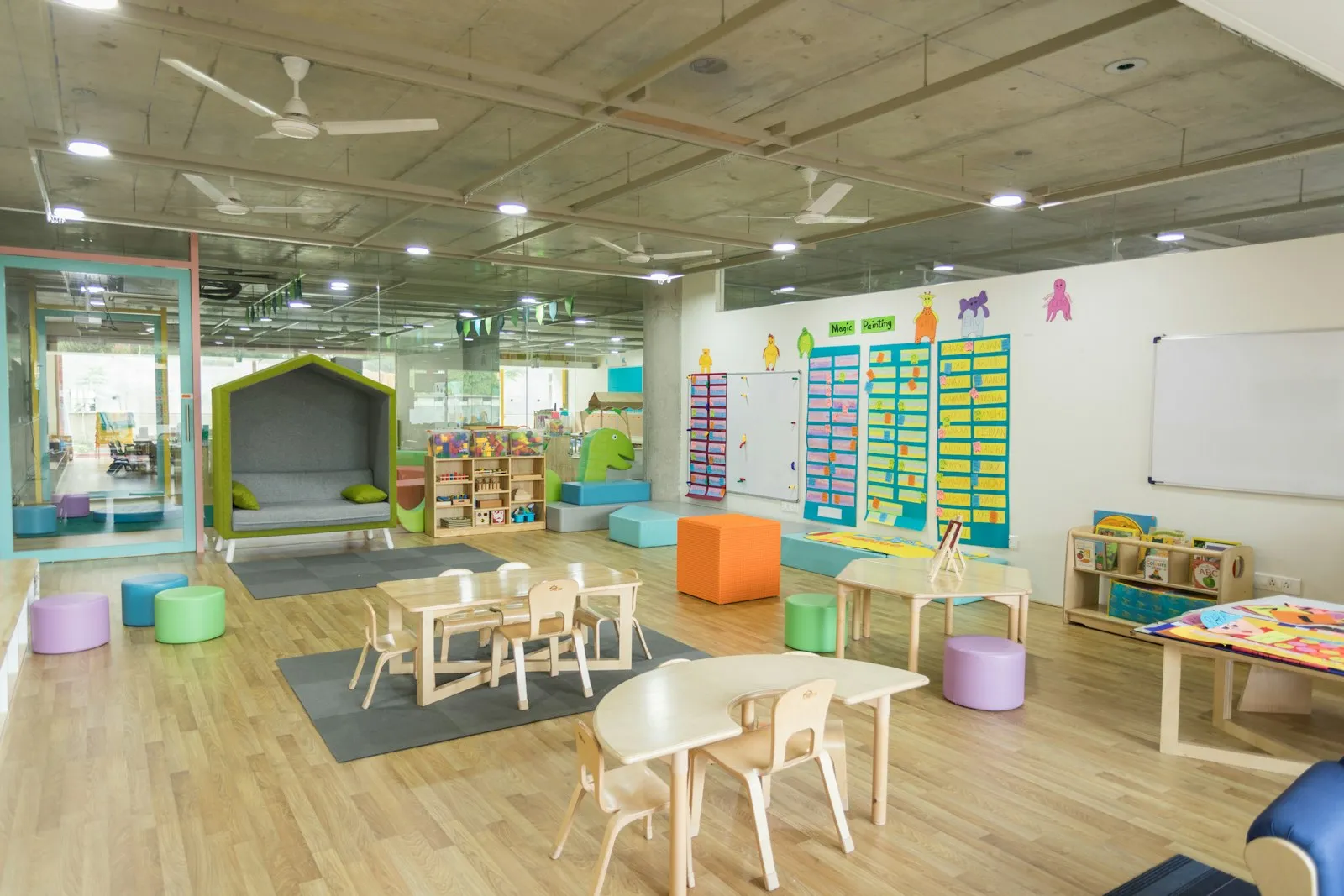 A bright nursery classroom with small tables, chairs and shelves of toys
