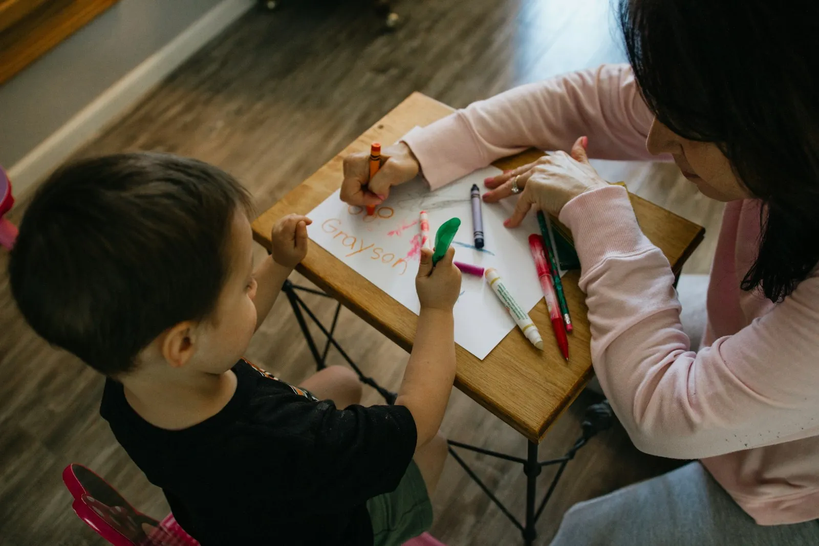 An adult and a young child colouring together at a table