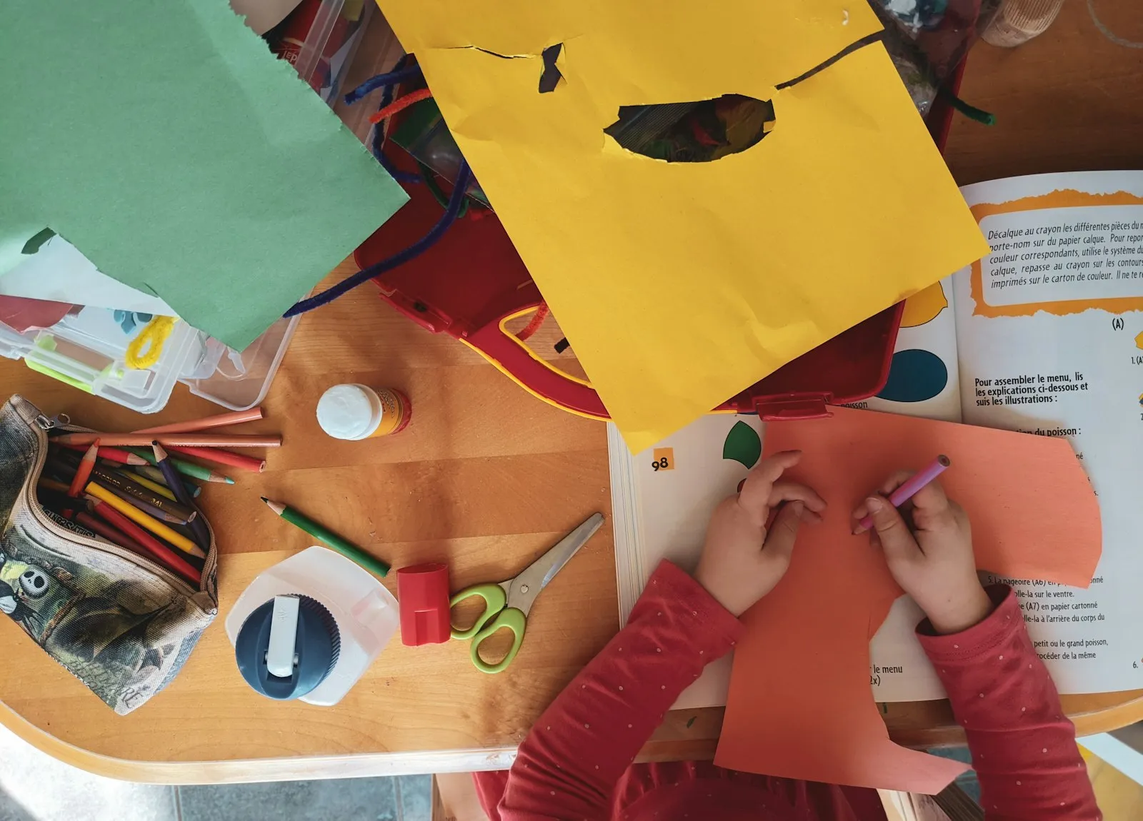 Children cutting and sticking colourful paper at the craft table